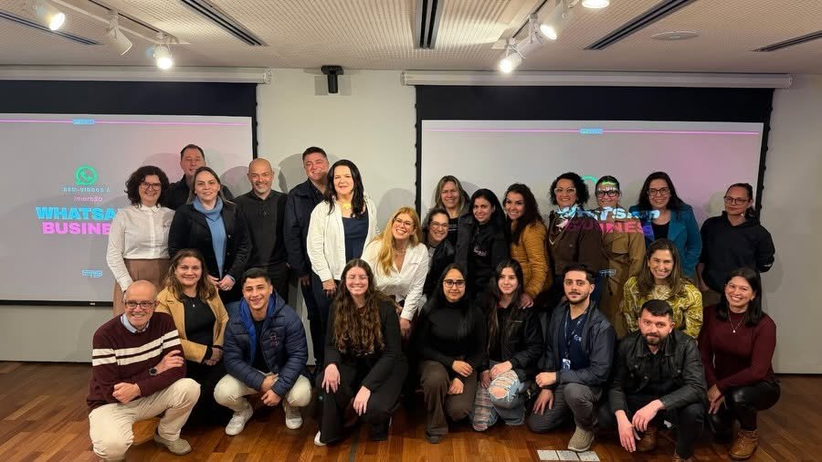 Turma presencial da Imersão WhatsApp Business reunida em sala, em frente ao telão da imersão